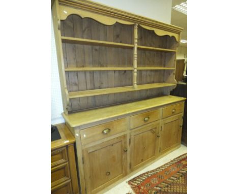 An Edwardian pine dresser, the three shelf open boarded plate rack with central pilaster decoration, over a base of three dra