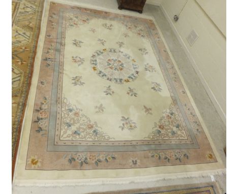 A Chinese carpet, the central circular floral medallion in green, pink and taupe on a cream floral decorated ground within pi