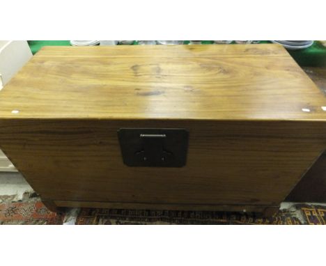 A large teak Eastern style chest with brass lock and handles, on bracket feet