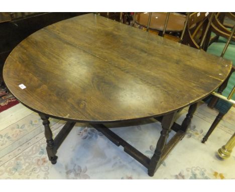 An 18th Century oak oval gate leg drop leaf dining table, the plain top above a single end drawer opposite a dummy drawer, ra