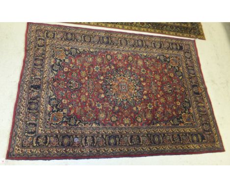 A Meshed carpet, the central burgundy field with stylised foliate decoration in blue, salmon, madder and burgundy, within dar