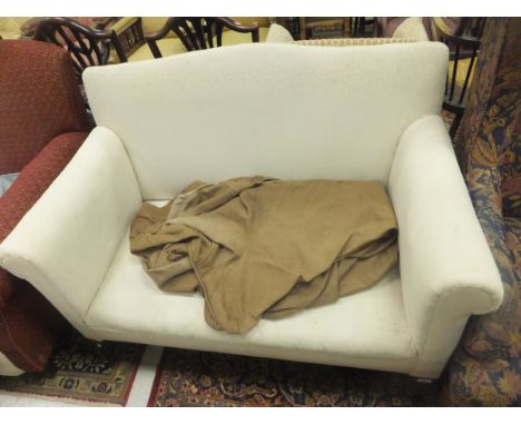 An Edwardian hump back scroll arm two seat sofa with loose covers