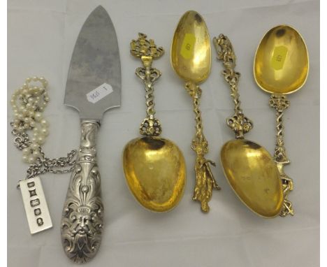 A set of four Continental white metal and gilded spoons, each with a different finial, together with a silver handled cake sl