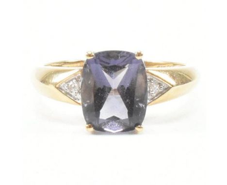 A hallmarked 9ct yellow gold, iolite and diamond ring. The ring having a rounded rectangular cut purple stone flanked by an a