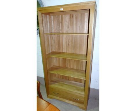A modern light oak full height bookcase with drawer under