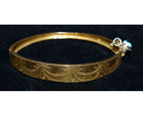A continental yellow metal stiff hinged bangle with engraved swag decoration, 13.7 gms