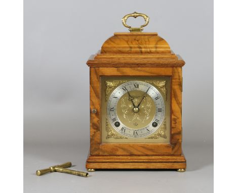 An Elliot 8 day clock in burr walnut case. With square gilt brass dial. Housing a two train movement striking half-hourly on 