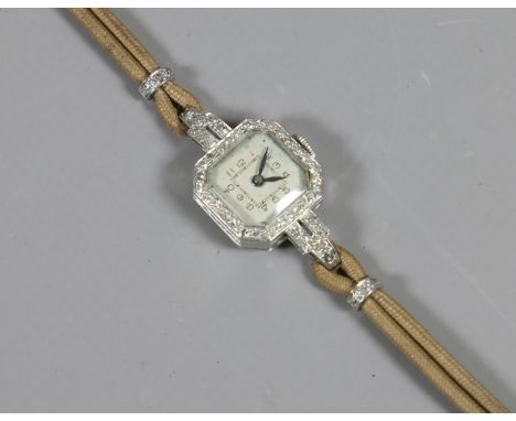 An Art Deco platinum and diamond cocktail watch with square canted dial having Arabic numeral markers.