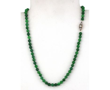 A polished jade bead necklace on a yellow metal (tested 18ct gold) clasp set with diamonds and a pearl, L. 42cm.