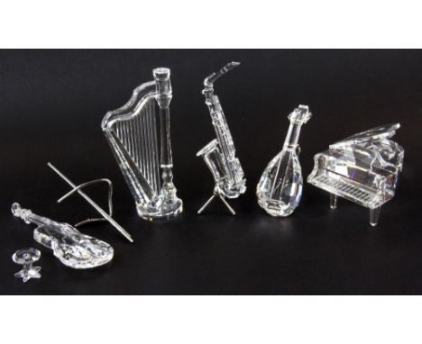 A quantity of boxed Swarovski crystal instruments including a saxophone, harp, cello, lute and a piano and stool, tallest H. 