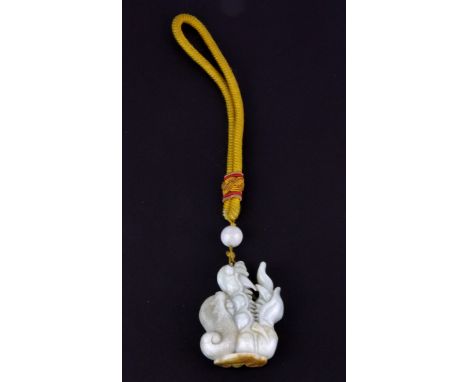 A superb Sino-Tibetan carved celadon and russet jadeite jade dragon head protective amulet and bead mounted on a yellow silk 