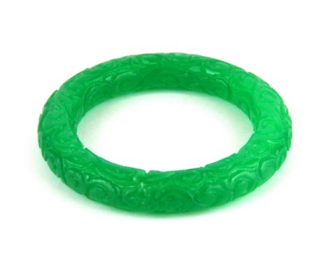 A Chinese carved apple green jade/ hardstone bangle, W. 13mm internal Dia. 6cm.