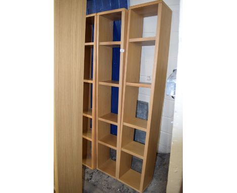 A trio of modern light wood finish narrow bookcases