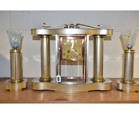 AN ART DECO STYLE CLOCK GARNITURE, the gold coloured metal case with chromed details, Arabic numerals, 8 day movement, bell s