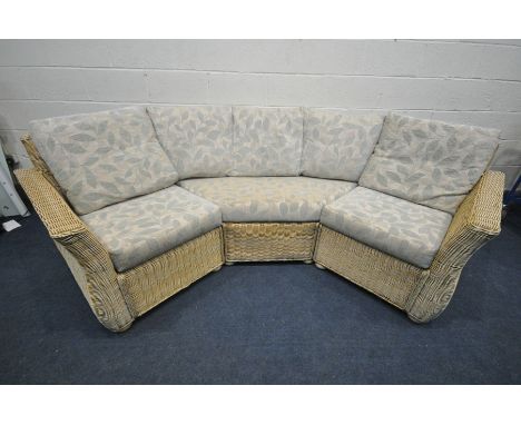 A LIGHT WICKER ROUNDED CONSERVATORY SOFA, with floral cushions, breaks into three sections