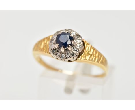 AN 18CT GOLD SAPPHIRE AND DIAMOND CLUSTER RING, centring on an eight claw set, circular cut blue sapphire, within a surround 