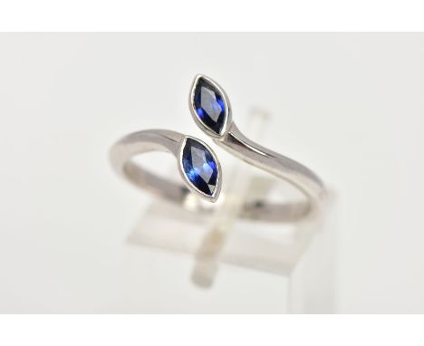 AN 18CT WHITE GOLD SAPPHIRE RING, of a cross over design, set with two marquise cut blue sapphires at each terminal, to a pla