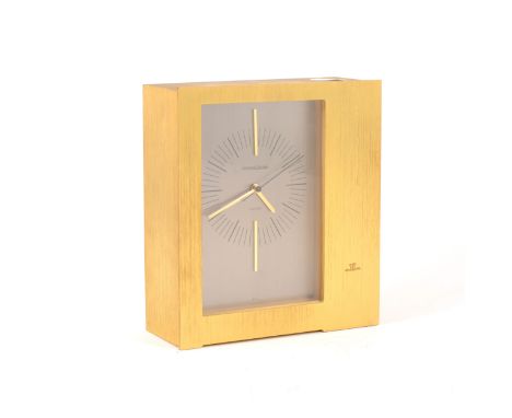 Jaeger LeCoultre Electric mantle clock, asymmetrical brushed gilt metal case, silvered rectangular dial with oversized gilt b
