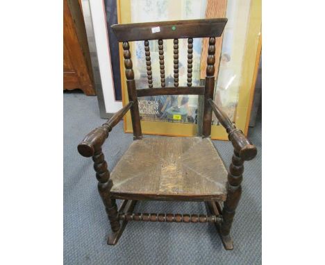 A late 19th century child's rocking, bobbin turned spindles, rattan seat on turned legs 