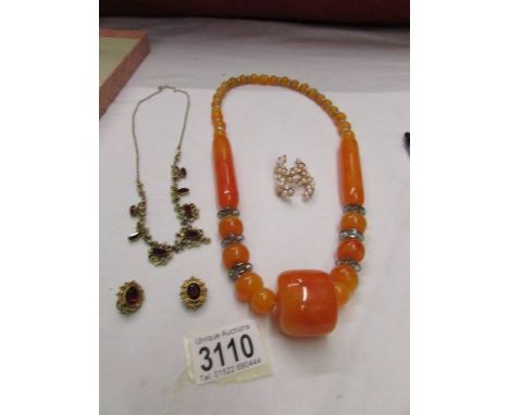 A matching necklace and earrings, a bakelite necklace and a gold coloured chain necklace with stone.