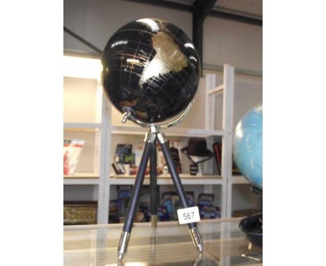 A black globe with gold mapping on a tripod base.