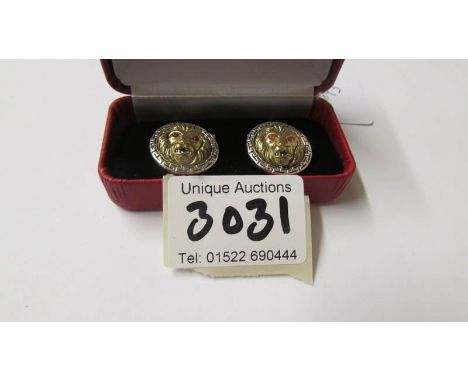 A pair of silver 'Versace' style lion mask cuff links with ruby eyes.