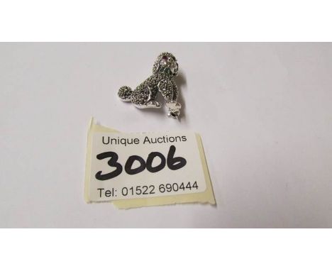 A silver marcasite dog brooch set with ruby coloured eyes.
