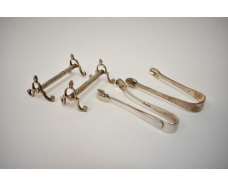 A pair of Victorian silver knife rests and two pairs of sugar tongs.  111g