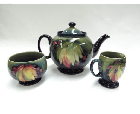 A Moorcroft "Leaf &amp; Berry" pattern teapot, signed to base, approximately 15cm tall, with matching jug and sugar bowl