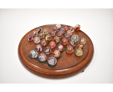 A late 19th Century mahogany solitaire board with mostly Victorian handmade marbles including Latticinio core swirls, white, 