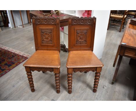 Circa 1890 in the manner of "James Shoolbred" a pair of oak Arts &amp; Crafts hall chairs with carved panel backrest and frie
