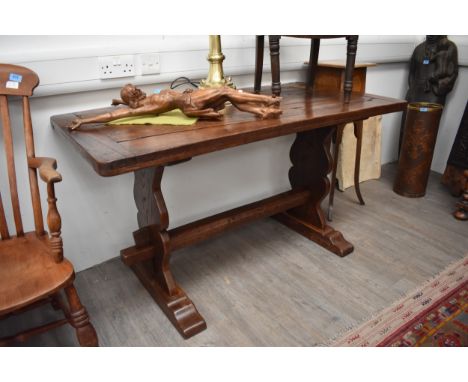 An 18th Century country cottage oak trestle end refectory dining table of small proportions, the cleated end plank top on sha