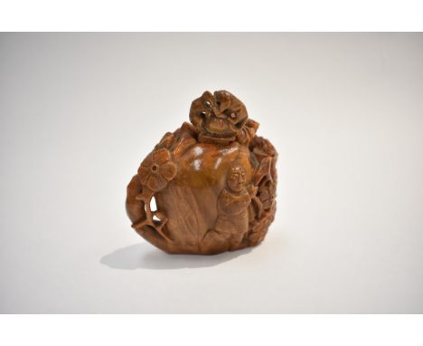 An early 20th Century Chinese carved butterscotch amber vessel depicting figures surrounded by flowers, surmounted by a lid w