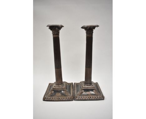 A pair of Georgian plate on copper Corinthian column candlesticks with crested detail, well worn, 29.5cm tall
