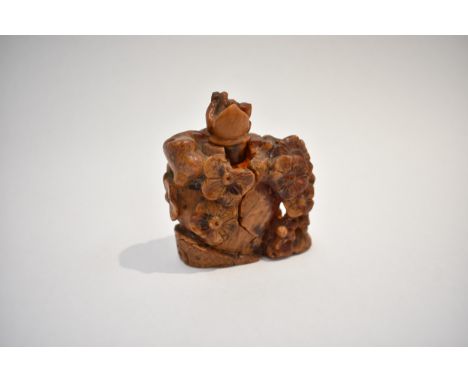 An early 20th Century Chinese butterscotch root amber carved vessel of unusual form decorated in relief with flowers, (a/f) 6