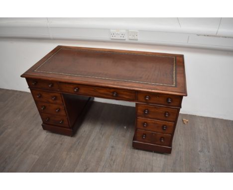 Circa 1860 a mid-Victorian mahogany twin pedestal desk the gilt tooled leather writing surface over nine drawers with turned 