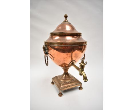 A Georgian copper tea urn with ram's head drop handle, raised on square base with four feet, 44cm tall