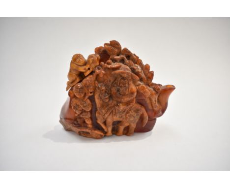 An early 20th Century Chinese carved root amber teapot, heavily carved in relief with figures, one riding a donkey, the lid i