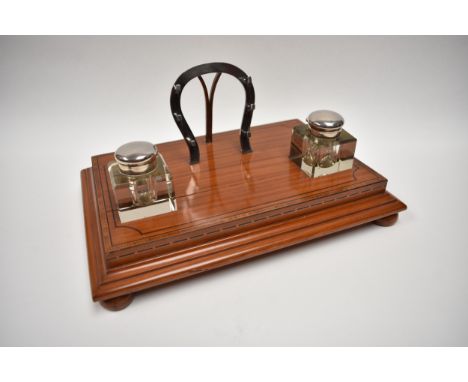 An equestrian related desk stand mounted with two silver topped inkwells with a plated horseshoe pen holder, crack to top, 15
