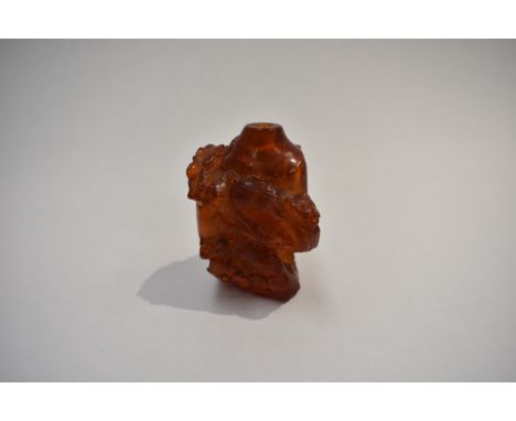 An early 20th Century Chinese carved amber snuff bottle decorated in relief lacking stopper, 8cm x 4cm, 34g