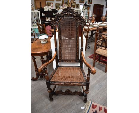 A 17th Century revival carved walnut and cane raise back and seat armchair having cherub mask and acanthus leaf with harebell