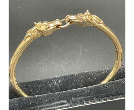 A 9ct gold horse themed bangle., Approximate total weight 41.5g, with two horse heads.