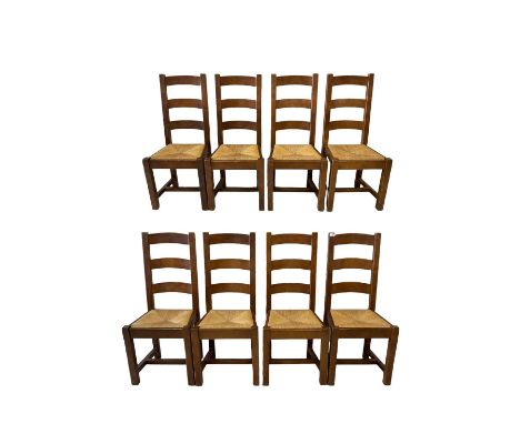 Set eight oak dining chairs, the ladder back over rush seat, raised on squared supports, united by H stretcher 