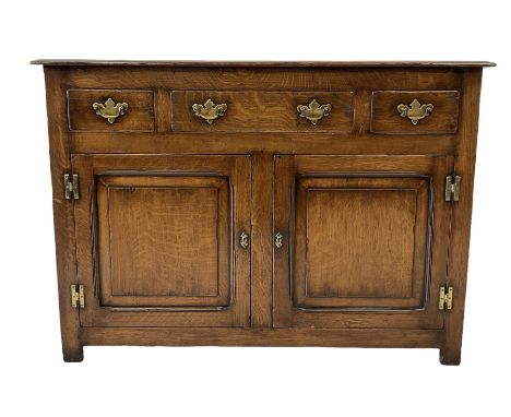 Oak sideboard, the projecting rectangular top over one long and two short drawers over two cupboard doors opening to reveal o