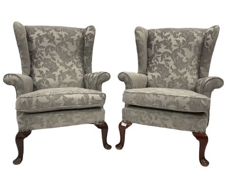 Pair of wingback armchairs upholstered in light grey fabric, raised on cabriole supports 