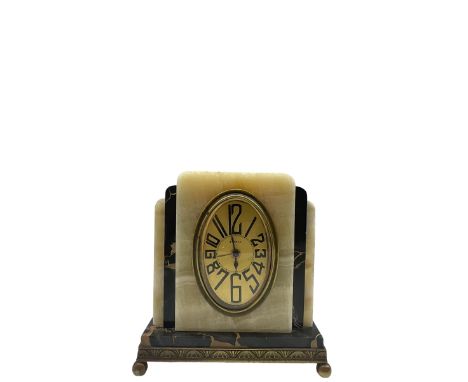 A compact 20th century Fisco French Art Deco cream onyx and gold veined black marble alarm clock raised on a shallow brass pl