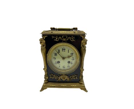 A French mantle clock c1900 in an ebonised case with brass mounts and carrying handle, enamel dial with Arabic numerals, minu