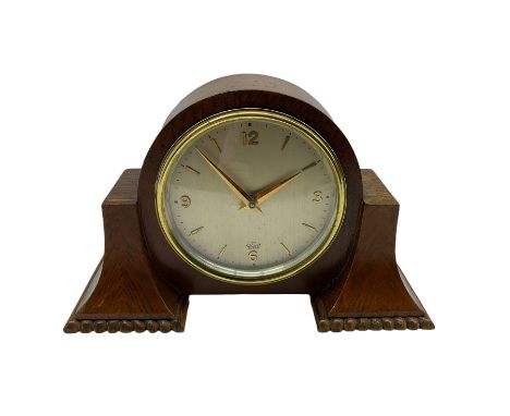 A small mid-20th century English made mantle clock in a round oak case with protruding side supports, Elliot spring driven ei