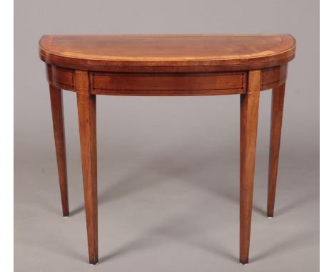 A George III mahogany bow fronted card table raised on square tapering supports. Banded in satinwood and coromandel and with 