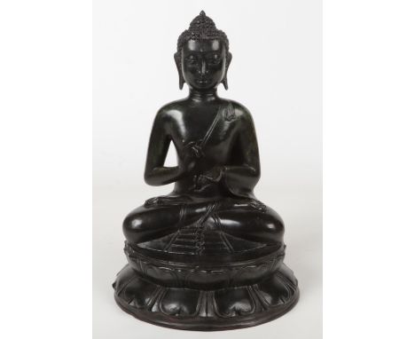 A 19th century Sino-Tibetan cast metal statue of a seated Buddha. Raised on a circular lotus plinth. With dark verdigris pati